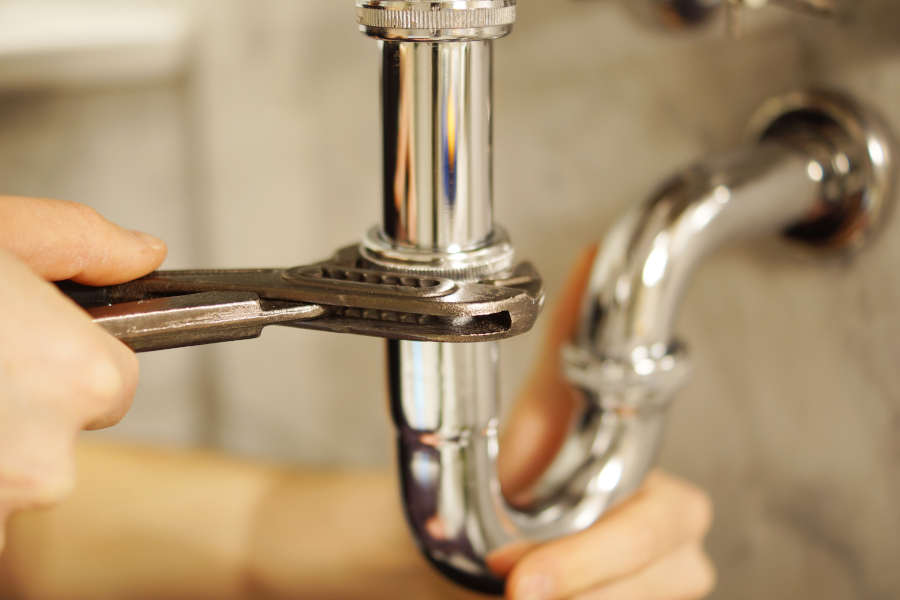 Plumbing repair service. Plumbing repair service. Professional installer with spanner checking pipe.